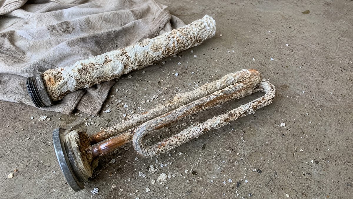 Water heater heating element and anode rod caked in hard water calcium scale pulled from a Hollister home