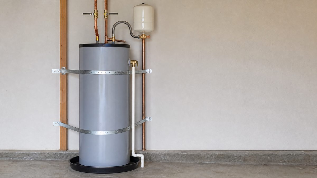 Newly installed tank water heater with copper connections, thermal expansion tank, seismic straps, and drip pan in a Hollister garage
